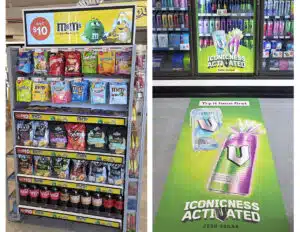 Confectionery display with an advertising screen alongside energy-drink advertising on a refrigerator and shop floor.
