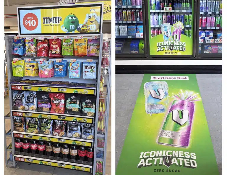 Confectionery display with an advertising screen alongside energy-drink advertising on a refrigerator and shop floor.