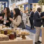 Grocery buyers discussing food samples with exhibitors at a professional trade fair