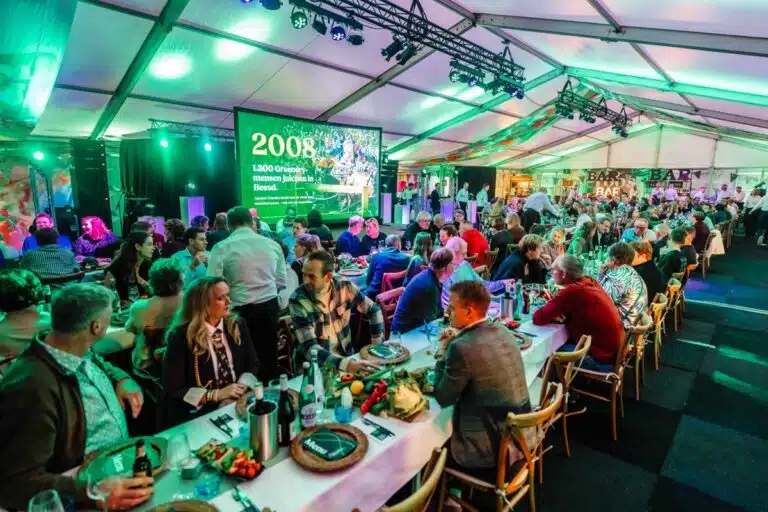 Guests seated at long dining tables beneath green lighting at The Greenery’s anniversary event