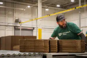 International Paper employee handling stacked cardboard on a production line