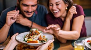 Two diners looking at a plate of food served at a table.