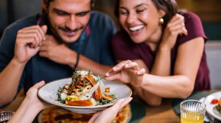 Two diners looking at a plate of food served at a table.
