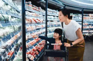 Woman and child beside refrigerated supermarket shelves