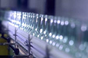 Clear glass bottles moving along an O-I manufacturing line