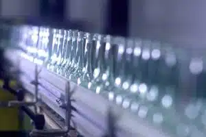 Clear glass bottles moving along an O-I manufacturing line