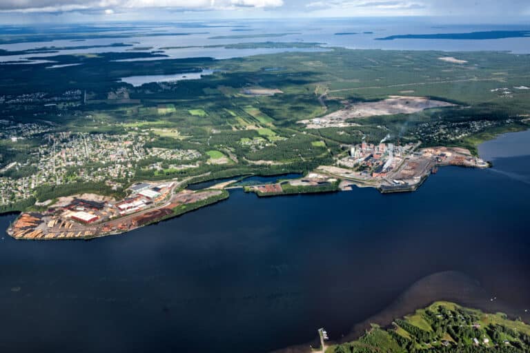 Aerial view of a paper mill beside water and forest at Munksund.