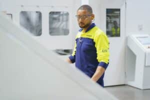 Smurfit Westrock machine operator wearing safety glasses and a yellow and navy uniform