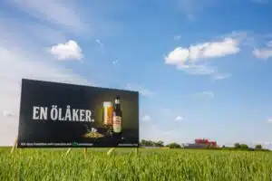 Mariestads beer sign in a green barley field under a blue sky