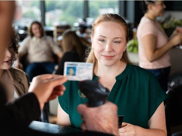 A member of staff scans a driving licence while a customer waits at a counter
